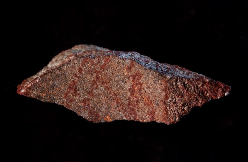 Roca de silcreta hallada en la Cueva de Blombos que presenta un dibujo realizado con un lápiz de ocre rojo por los primeros Homo Sapiens en lo que ahora es Sudáfrica