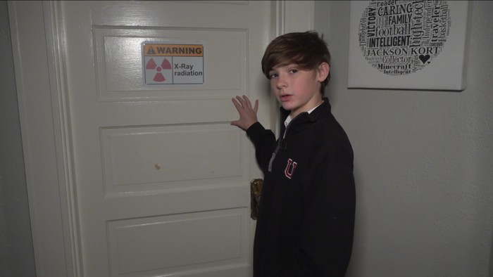 Jackson Oswalt, de 14 años, muestra el letrero en la puerta de su laboratorio de advertencia de radiación de rayos X