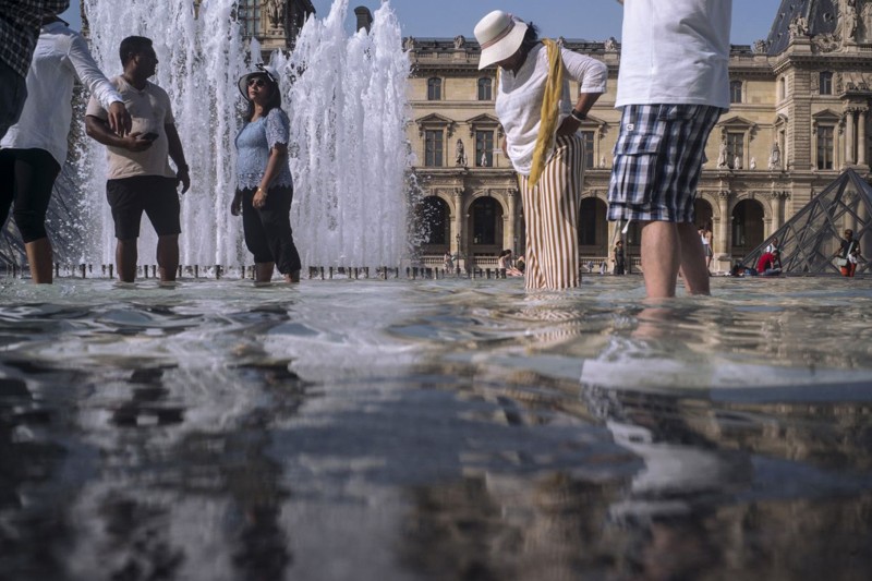 Gente refrescándose en las fuentes junto al Museo del Louvre en París, Francia, el miércoles 24 de julio de 2019