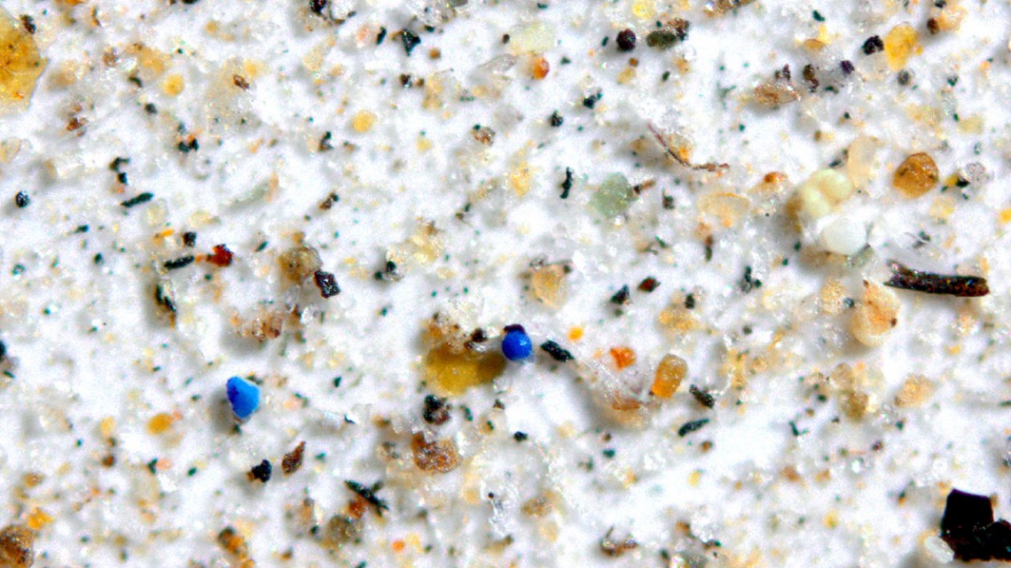 Partículas de microplástico azul rodeadas de polvo, minerales y carbón se asientan en un filtro