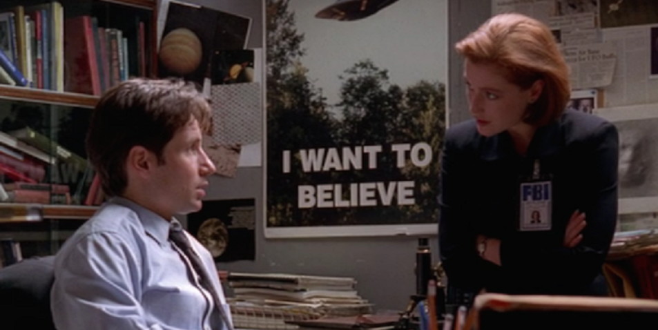 Fotograma donde se ve a Fox Mulder (David Duchovny) y a Dana Scully (Gillian Anderson). entre ellos, el icónico cartel que reza "I want to Believe"