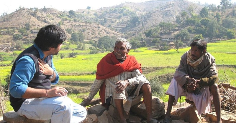 Hansa Ram, el ex líder de la aldea, vestido con un chal rojo mientras conversa con dos aldeanos