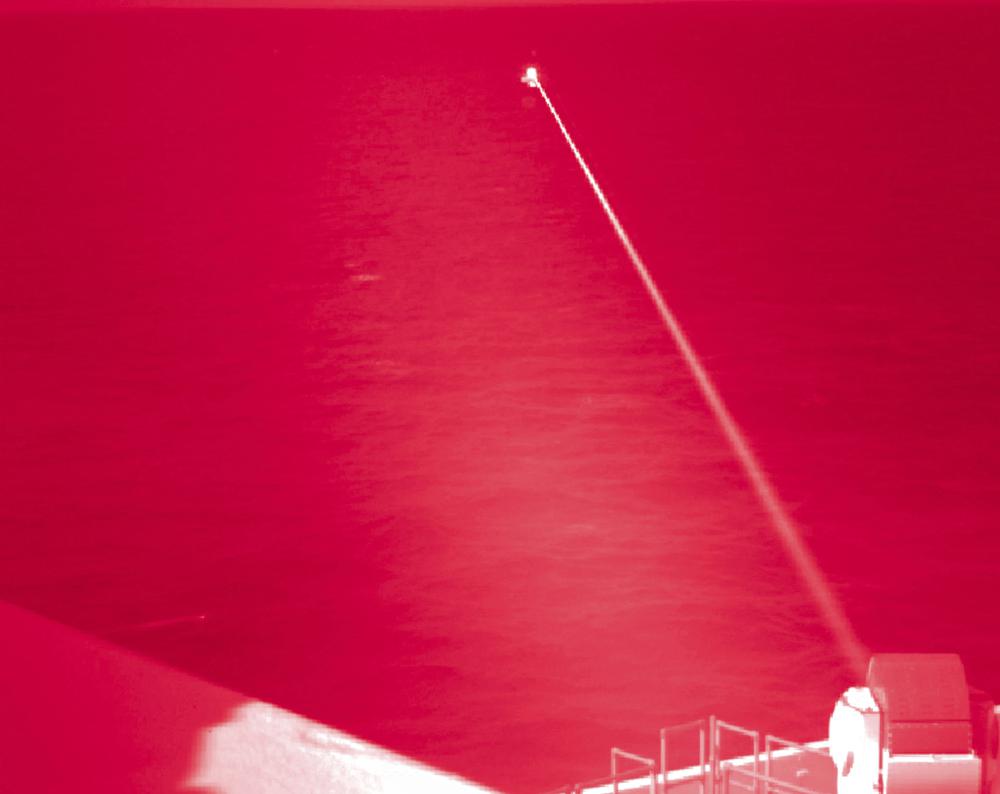 En esta foto en infrarrojos de la Marina de EE. UU., el USS Portland dispara un sistema de armas láser contra un objetivo que flota en el Golfo de Adén el martes 14 de diciembre de 2021