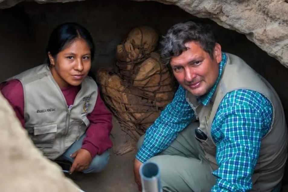 Los arqueólogos Yomira Silvia Huamán Santillán y Pieter Van Dalen, responsables del Proyecto Cajamarquilla, posan delante de la momia hallada recientemente en ese complejo arqueológico
