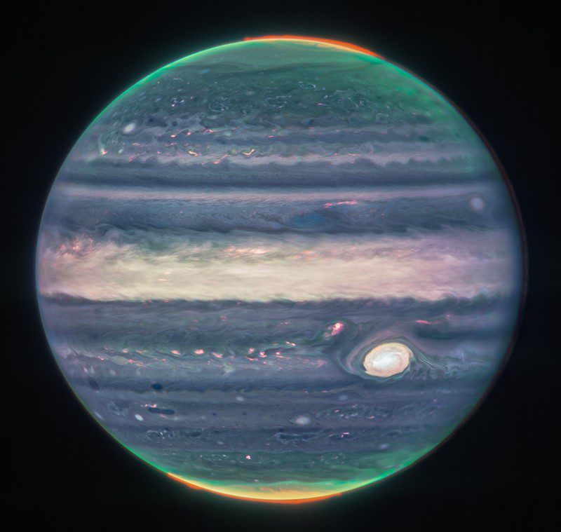 Una imagen compuesta de Júpiter tomada por la NIRCam del telescopio espacial James Webb; el resplandor naranja alrededor de los polos es la aurora