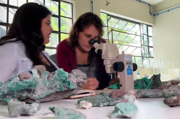 La investigadora Fernanda Avelar Santos mira a través de un microscopio junto a la también investigadora Giovana Diorio de la Universidad Federal de Paraná