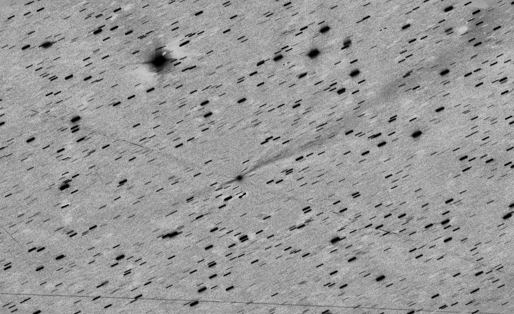 Imagen apilada de 3I/ATLAS basada en 20 exposiciones de 100 segundos cada una, tomadas a las 4:15 UTC del 20 de noviembre de 2025. El campo mostrado tiene unas dimensiones de 16,7 minutos de arco por lado, lo que equivale a 1.6 millones de kilómetros a la distancia de 3I/ATLAS de 326 millones de kilómetros. La dirección del Sol es hacia la parte inferior izquierda (opuesta a la flecha del panel central). La imagen muestra dos líneas estrechas dirigidas lateralmente desde el eje 3I/ATLAS-Sol y que crean un patrón cruzado con la cola y la anticolla a lo largo de ese eje.
