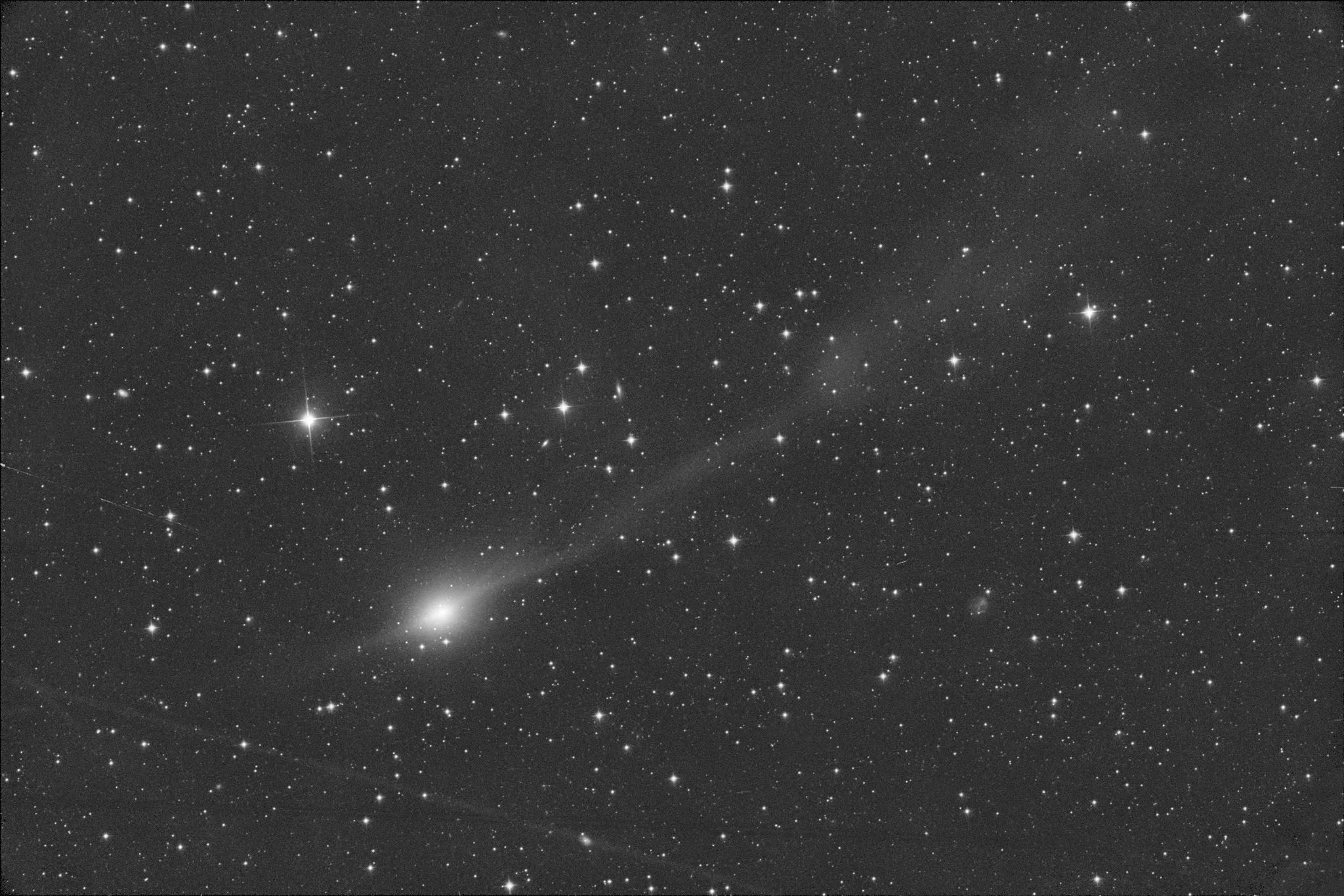 Imagen apilada de 3I/ATLAS basada en 20 exposiciones de 100 segundos cada una, tomadas a las 4:15 UTC del 20 de noviembre de 2025. El campo mostrado tiene unas dimensiones de 16,7 minutos de arco por lado, lo que equivale a 1.6 millones de kilómetros a la distancia de 3I/ATLAS de 326 millones de kilómetros. La dirección del Sol es hacia la parte inferior izquierda (opuesta a la flecha del panel central). La imagen muestra dos líneas estrechas dirigidas lateralmente desde el eje 3I/ATLAS-Sol y que crean un patrón cruzado con la cola y la anticolla a lo largo de ese eje.